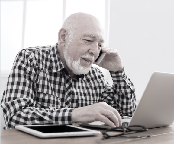 Photo of elderly man on the phone using computer